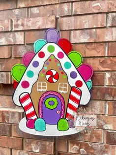 a decorative gingerbread house hanging on the side of a brick building with colorful decorations