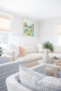 a living room filled with white furniture and lots of pillows on top of it's couches