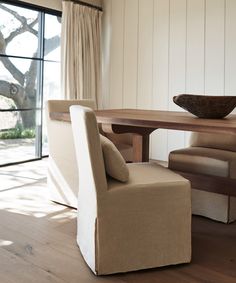 a chair and table in a room with wood flooring, white walls and windows