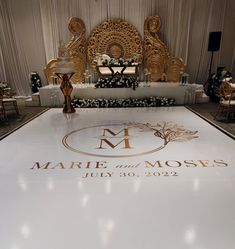 a large white dance floor with gold lettering on it and chairs around the centerpiece