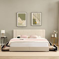 a white bed sitting in a bedroom next to two pictures on the wall above it