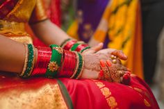 the brides hands are covered with hennap and bracelets as they sit together