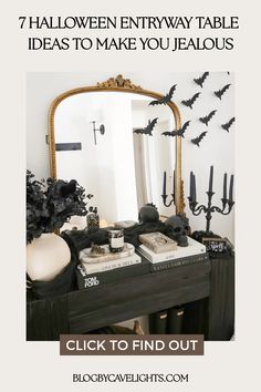 a halloween entryway table with candles and decorations on it, including bats in the mirror