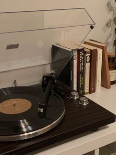 a record player sitting on top of a table next to some books and a plant