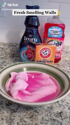 a bowl filled with pink liquid next to two bottles of mouthwash and cleaning soap