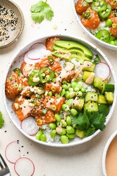 two bowls filled with different types of food on top of a white table next to utensils