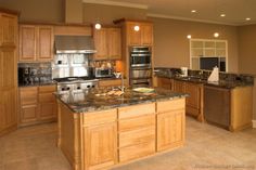 a large kitchen with granite counter tops and wooden cabinets, along with stainless steel appliances