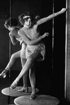 an old photo of two women in flappers and garters, one is dancing