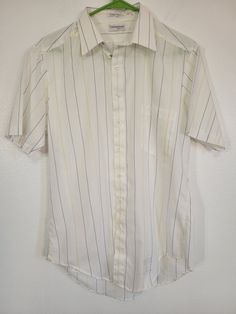 For when you need a vintage office wardrobe! We gotcha covered! Vintage 1980s Counterpoint white blue/yellow stripe short sleeve shirt  men's chest 40" made in USA Looks straight out of the package! Please see our other listings for more vintage garments with new items added nearly daily. PLEASE check the measurements as vintage clothing sizes may not comparable to contemporary sizes. Measurements: Label size: 16 Shoulder-to-shoulder: 18" Chest across: 20" Sleeve from shoulder: 9" Length in back from base of collar: 31" Pete's Obsolete is smoke-free. We present garments as honestly as possible and point out any known flaws. We leave cleaning and/or repair decisions to you. Please note, if you are interested in our wool collection, we cannot guarantee that we can identify every nearly invis White Business Top With Vertical Stripes, White Vertical Stripes Business Top, White Vertical Stripe Button-up Shirt, White Vertical Stripes Top For Formal Occasions, White Vertical Striped Top For Formal Occasions, Formal White Tops With Vertical Stripes, Formal White Top With Vertical Stripes, White Short Sleeve Dress Shirt For Formal Occasions, Retro Short Sleeve Shirt With Vertical Stripes