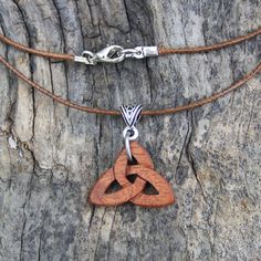 a wooden pendant is hanging on a leather cord with a silver chain attached to it