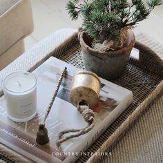 a table with a candle, potted pine tree and other items on the tray