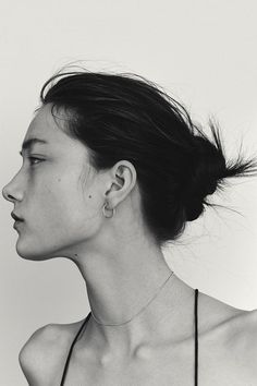 a black and white photo of a woman with her hair blowing in the wind, looking off to the side