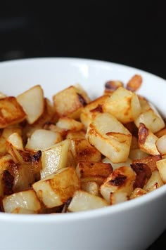 a white bowl filled with cooked potatoes on top of a table