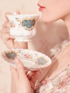 a woman holding a cup and saucer in her hands