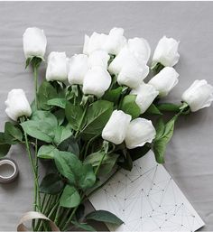 a bouquet of white roses next to a pair of scissors on a piece of paper