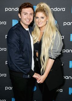 a man and woman standing next to each other in front of a blue wall with the words panda on it