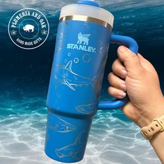 a hand holding a blue travel mug in the ocean