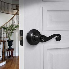 an open door with a black handle on it and a white staircase in the background