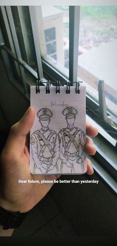 a hand holding a notepad with a drawing of two people in uniforms on it