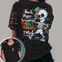 a woman wearing a black rock paper scissors t - shirt with the image of a skeleton holding a baseball bat