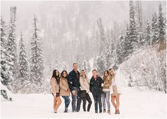 a group of people standing next to each other on top of snow covered ground with trees in the background