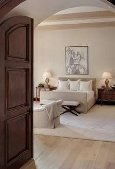 an open door leading to a living room with white furniture and wood accents on the walls