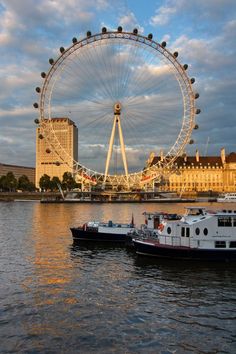 two boats in the water near a large ferris wheel