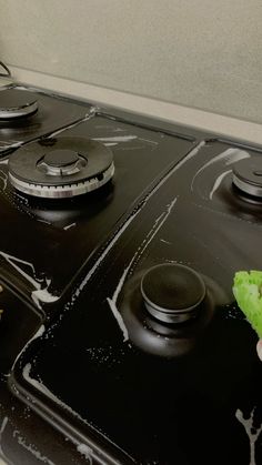 someone is cleaning the stove top with a sponge and a green leafy item in their hand