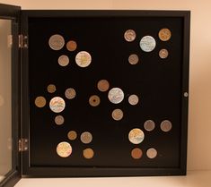 a display case with many different types of coins in it's black frame and glass doors