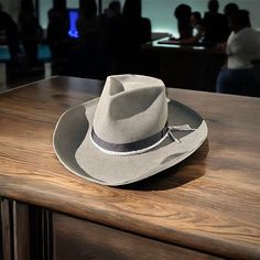 The Rough Cut is a cowboy hat like you've never seen before. Classic at first sight- but with plenty of modern twists. Just the color scheme is much more modern and urban than the classic brown or beige cowboy hats of yesteryear. Featuring a vintage style binding on the underside of the brim. Yet, structured with a K. Doughty signature "diamond cut crown". Decorated with a nice black grosgrain ribbon and bow and a winged dog pin. Lined with white satin featuring red/white parlor logo. Tall and Wide for the bold. Size 59cm : 7 3/8 Western Style Wide Brim Gray Hat, Gray Western Hats For Rodeo, Adjustable Western Gray Hat Band, Adjustable Gray Western Hat Band, Felt Cowboy Hat, Felt Cowboy Hats, Classic Brown, Dog Pin, Rough Cut