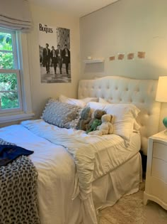 a white bed sitting in a bedroom next to a window with pictures on the wall