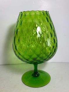 a green glass vase sitting on top of a table