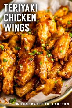 teriyaki chicken wings in a white bowl with sesame seeds and green garnish