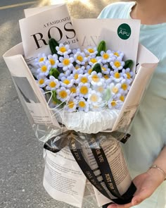 a woman is holding a bouquet of daisies