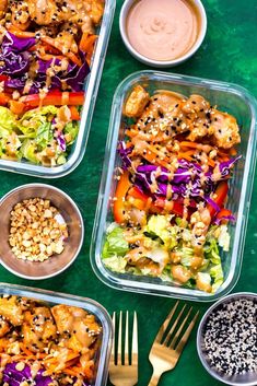 four plastic containers filled with food on top of a green tablecloth next to gold utensils