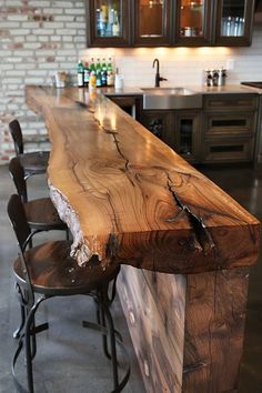 a wooden counter top sitting in the middle of a kitchen next to two bar stools