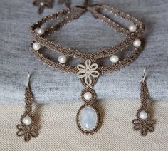 a necklace and earring set with pearls on the bottom is sitting on a piece of cloth