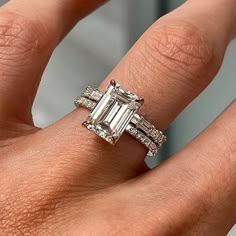 a woman's hand with an emerald and diamond ring on top of her finger