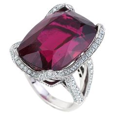 Introducing a breathtaking masterpiece of elegance, this exquisite ring features a very rare 38.21 carat rubellite as its centerpiece. Sourced from the renowned Cruzeiro Mine in Brazil, this unique tourmaline exhibits an intense red hue reminiscent of the most coveted Burmese rubies. Set in 18 karat white gold, this resplendent gem is accentuated by 230 round cut diamonds with a total weight of 2.91 carats. Graded G in color and VS in clarity, these diamonds add a brilliant sparkle to this timel Rubellite Ring, Double Halo Engagement Ring, Amethyst Ring Engagement, Tourmaline Jewelry, Silver Engagement Rings, Bling Rings, Rings Jewelry, Lovely Jewellery, Gorgeous Jewelry