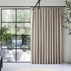 a living room filled with furniture and a large window covered in beige striped curtain panels