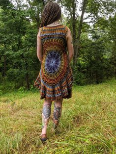 a woman in a dress walking through the woods with tattoos on her legs and arms