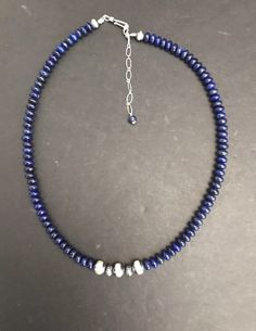 sterling shaded lapis bead necklace. The necklace measures 16 inches Silver Jewelry With Faceted Beads Made Of Lapis Lazuli, Silver Jewelry With Faceted Beads In Lapis Lazuli, Silver Lapis Lazuli Necklace With Polished Beads, Lapis Lazuli Gemstone Beads Necklace In Silver, Silver Lapis Lazuli Necklace With Gemstone Beads, Silver Lapis Lazuli Gemstone Beads Necklace, Sapphire Lapis Lazuli Beaded Necklace, Sterling Silver Rondelle Necklace With Polished Beads, Single Strand Lapis Lazuli Round Bead Necklace