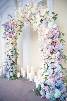 a floral arch is decorated with candles and flowers