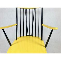 a yellow chair with black metal bars on the back