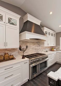 a large kitchen with white cabinets and stainless steel stove top oven in the center of the room