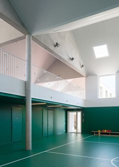 an indoor tennis court with green flooring and white railings on the second story