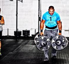 two men are doing exercises with dumbs in the gym while one man is holding a barbell