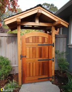 a wooden gate in the middle of a yard with plants and trees around it,