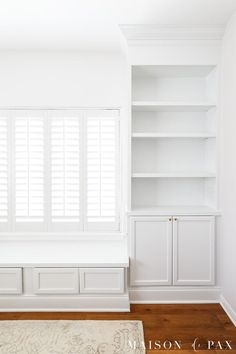 an empty room with white walls and wooden floors, built - in bookshelves