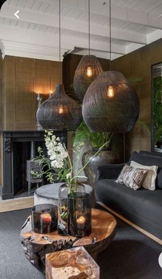 a living room filled with furniture and lamps hanging from the ceiling next to a fire place